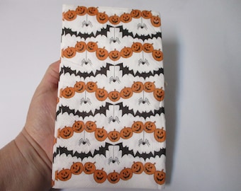 May include: White paper napkins with a Halloween theme. The napkins feature a repeating pattern of orange pumpkins with black eyes and mouths, black bats, and black spiders.