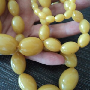 Pode incluir: Um longo fio de contas de &acirc;mbar amarelo de forma oval. As contas s&atilde;o enfiadas em um cord&atilde;o e est&atilde;o dispostas em um padr&atilde;o solto e fluido.