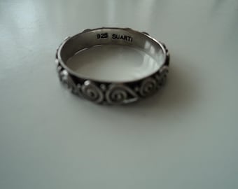 May include: A silver ring with a decorative swirl design and the inscription "925 SUARTI" on the inside.