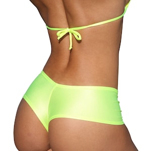 Puede incluir: Conjunto de bikini amarillo neón. La parte superior es de estilo triangular con finas correas que se atan en el cuello y la espalda. Los shorts a juego son de talle bajo con un corte de pantalón corto. La tela tiene un ligero brillo.