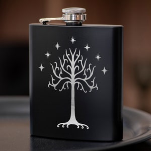 Pode incluir: Frasco de aço inoxidável preto com um design gravado em prata de uma árvore com estrelas.