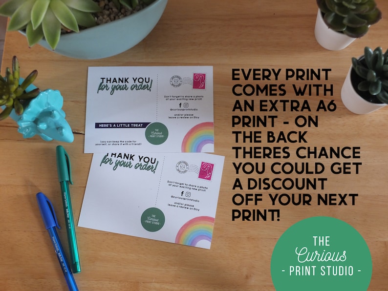 May include: Two thank you cards with a rainbow design. The text on the cards reads "Thank you for your order!" and "Here's a little treat". The cards are on a wooden surface with a green pen and two small potted plants.