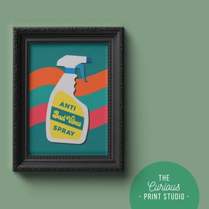May include: A framed print featuring a colourful illustration of a spray bottle labelled "Anti Bad Vibes Spray". The background is teal green with orange and red wavy lines.