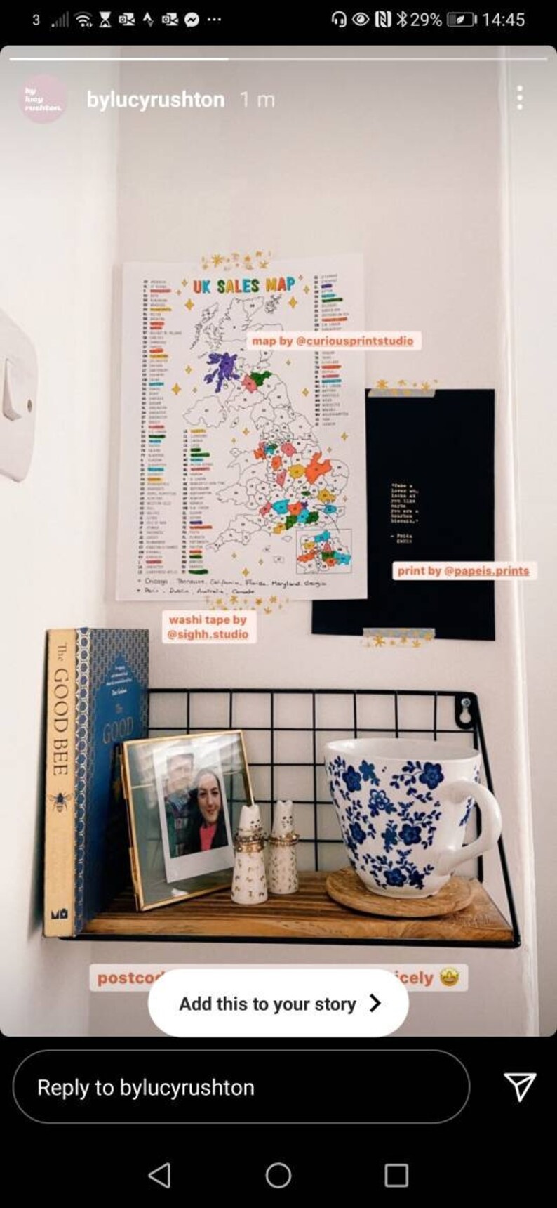 May include: A white wall with a colorful map of the UK sales map, a black framed print with white text, a wooden shelf with a gold framed photo, two ceramic salt and pepper shakers, a blue and white floral teacup, and a book titled "The Good Bee".