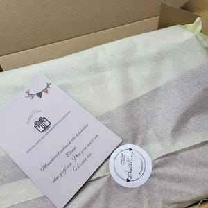 May include: A white box with a white tissue paper lining. The box contains a small card with the text "petite Pat PERSONALISERTE GESCHENKIDEEN F&Uuml;R KLEIN UND GROSS Manchmal nehmen die kleinsten Dinge den gr&ouml;&szlig;ten Platz in unserem Herzen ein" and a round sticker with the text "vielen Dank f&uuml;r Deine Bestellung".