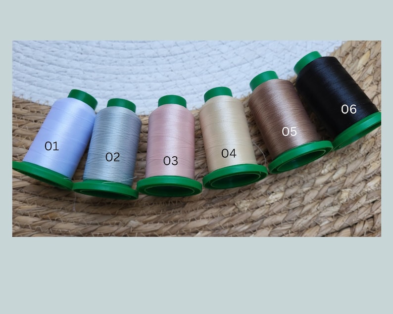 May include: Six spools of thread in different colors, labeled 01 through 06. The colors are light blue, silver, light pink, beige, light brown, and black.