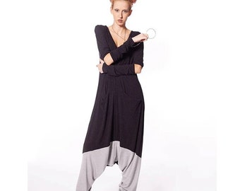 May include: A long-sleeved black jumpsuit featuring a deep V-neckline and a drop-crotch design. The lower portion of the legs is light gray, and the garment includes fitted sleeves and a relaxed silhouette that tapers toward the ankles.