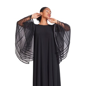 May include: A floor-length black dress featuring a round neckline and dramatic, wide, sheer sleeves. The sleeves are constructed from layers of black tulle or organza, accented with horizontal black ribbon trim that creates a structured, tiered effect.
