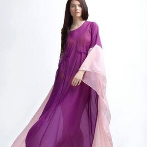 May include: A floor-length kaftan dress featuring a deep purple center panel and contrasting light pink side panels. The garment has a loose, flowing silhouette with wide, draped sleeves and a gathered waistline, crafted from a sheer, lightweight fabric.