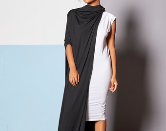 May include: A knee-length white dress featuring a sleeveless design and a round neckline, layered with a long, flowing black fabric wrap that drapes over one shoulder and extends to the floor, paired with black ankle boots.