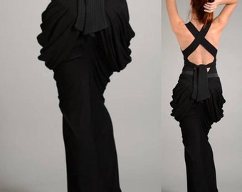 May include: A black maxi dress with a unique criss-cross back design and a gathered skirt. The dress features a black ribbon tied at the waist.