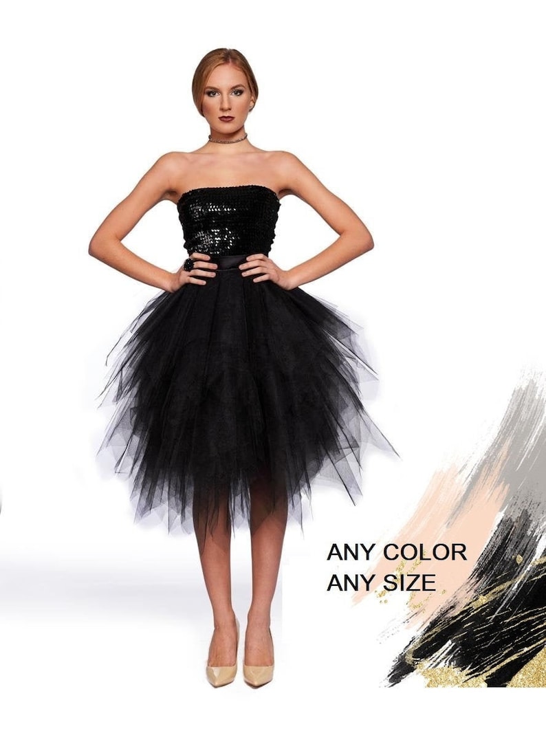 May include: A black strapless dress featuring a sequined bodice and a voluminous, layered tulle skirt that falls to the knees. The text ANY COLOR ANY SIZE is printed in black on the lower right side of the image, near a decorative brushstroke.