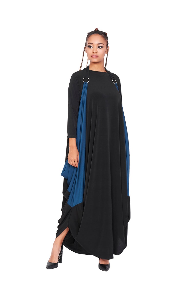 May include: A black maxi dress with a blue panel and silver rings on the straps. The dress has a loose, flowing fit.