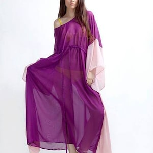 Puede incluir: Un vestido morado fluido y transparente con mangas largas y cintura con cord&oacute;n. El vestido presenta un panel rosa claro en contraste en las mangas y el dobladillo. La modelo lleva sandalias doradas.