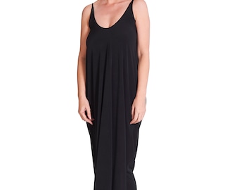 May include: A black maxi dress with a V-neck and spaghetti straps. The dress is loose-fitting and falls to the ankles. The person is wearing black ankle boots.