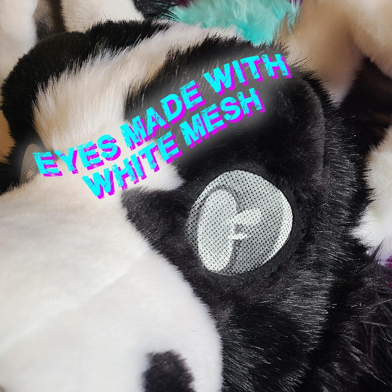 May include: Close-up of a furry, black and white costume head with the text "EYES MADE WITH WHITE MESH". The eye is a white mesh circle with a black outline. The fur is a mix of black and white.