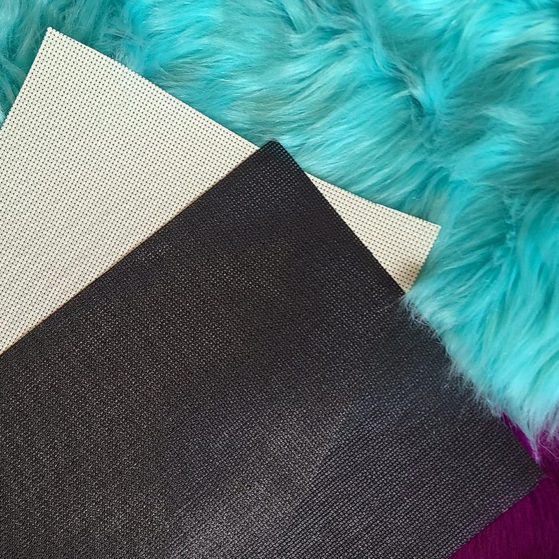 May include: Close-up of craft supplies featuring a black, textured sheet, a cream-colored sheet with small holes, and vibrant turquoise faux fur. The materials are arranged diagonally, showcasing their textures and colors.