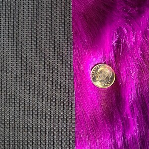 May include: A close-up shot of two contrasting textures: a dark gray mesh fabric and a vibrant, long-pile magenta faux fur. A U.S. dime coin is placed on the fur for scale, showing the texture and color variations.