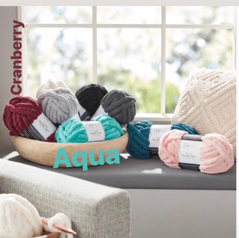 May include: A variety of chunky yarn in different colors, including cranberry, aqua, gray, and pink. The yarn is displayed in a wooden bowl and on a windowsill.