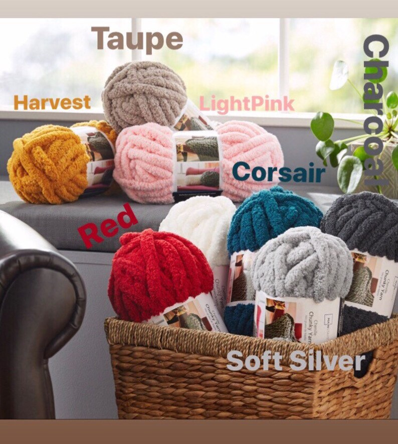May include: A basket filled with various colors of chunky yarn, including taupe, harvest, light pink, red, soft silver, charcoal, and corsair. The yarn is arranged in a circle around the basket.