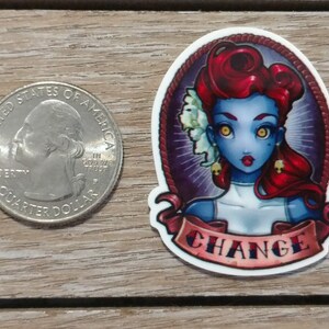 May include: A sticker featuring a blue-skinned woman with red hair and yellow eyes. She is wearing a white dress and has a skull earring. The sticker has a banner that says "CHANGE" in red and white letters.