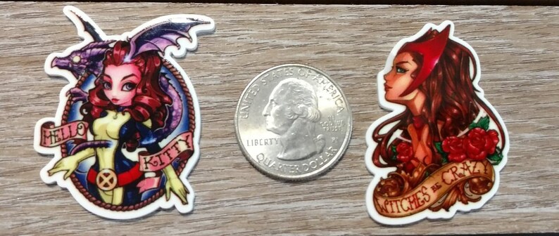 May include: Two colorful cartoon character stickers. The first sticker features a pink-haired woman with a purple dragon, with the text "Hello Kitty". The second sticker features a red-haired woman with a red crown, with the text "Witches be crazy".