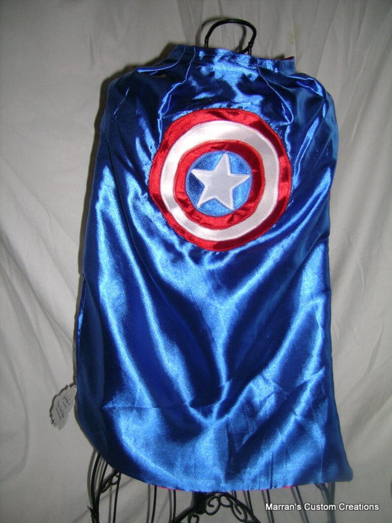 May include: Blue satin cape with a red, white, and blue embroidered circle with a white star in the center.