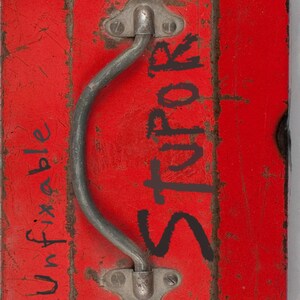 May include: Red metal toolbox with a silver handle and the word "Unfixable" written on the side. The toolbox has a worn, distressed look and the word "Stor" is written on the front.
