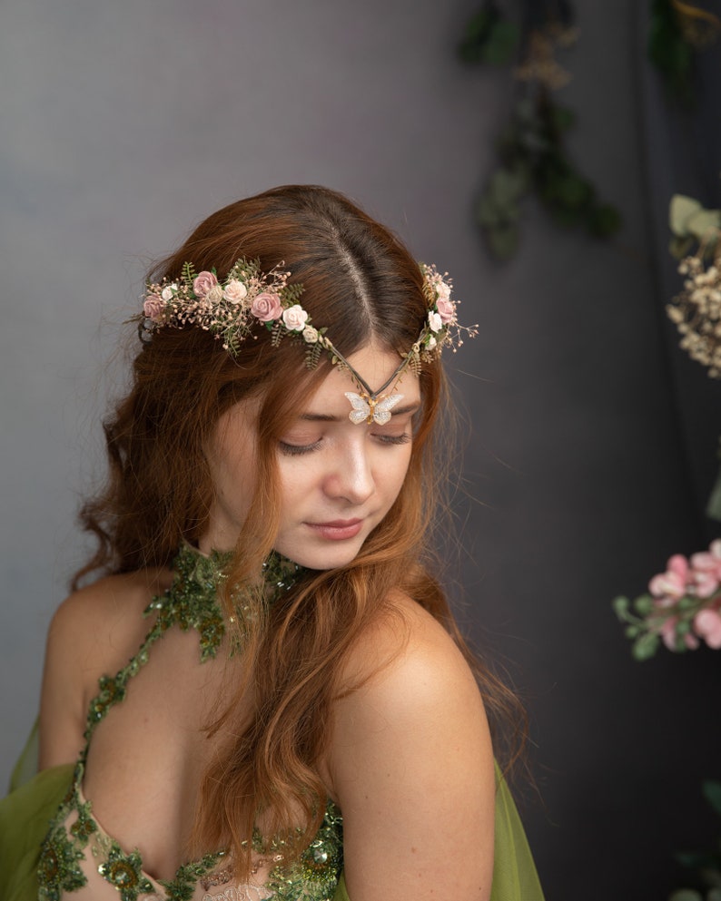 Peut inclure: Une femme aux longs cheveux roux porte une robe verte orn&eacute;e de fleurs. Elle porte une couronne florale d&eacute;licate avec un accent papillon sur son front.