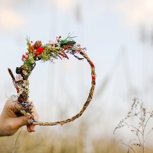 May include: A woven twig wreath with dried flowers and berries, including red, orange, and green accents.