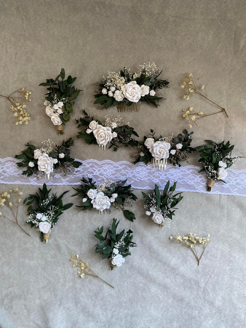 Puede incluir: Un surtido de accesorios florales nupciales, que incluyen peinetas y boutonnieres. Las piezas presentan rosas blancas, vegetaci&oacute;n y paniculata. Las boutonnieres est&aacute;n envueltas con hilo de bramante y las peinetas tienen un acabado dorado.