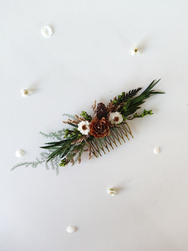 May include: A gold hair comb adorned with dried flowers and greenery. The flowers are white and brown, and the greenery is a mix of ferns and other foliage.
