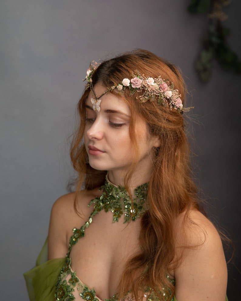 Peut inclure: Une femme aux longs cheveux roux porte une robe verte &agrave; paillettes et une couronne florale avec un accent papillon. La couronne est faite de fleurs d&eacute;licates et de verdure.