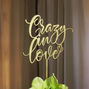 Pu&ograve; includere: Topper per torta in legno color oro con le parole "crazy in love" in un font corsivo. Il topper ha un piccolo cuore alla fine della parola "love".