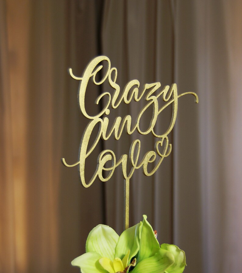 Pu&ograve; includere: Topper per torta in legno color oro con le parole "crazy in love" in un font corsivo. Il topper ha un piccolo cuore alla fine della parola "love".