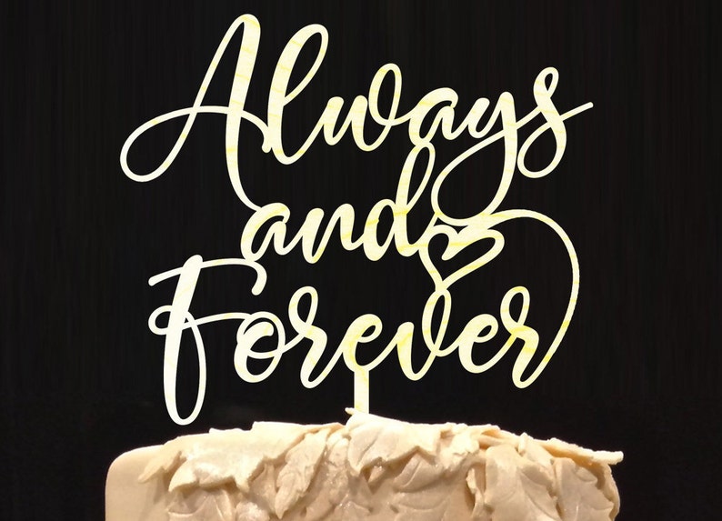 May include: White cake topper with the words "Always and Forever" in a cursive font with a heart symbol between the words.