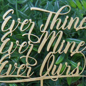 May include: Gold-colored wooden cake topper with the words "Everything ever Mine ever Ours" written in cursive.