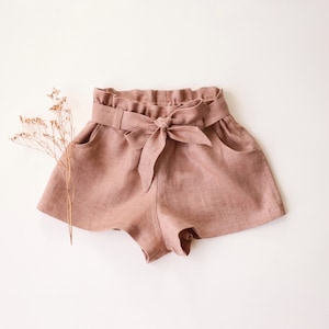 May include: A pair of light brown linen shorts with a wide waistband and a self-tie bow at the front.