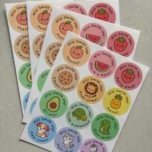 May include: A selection of circular stickers featuring charming illustrations of a peach, strawberry, and other cute characters. Each sticker includes the text "Miss Smith says" and a fun phrase, all on a white background.