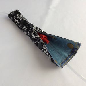 May include: A black and white bandana fabric pouch with a blue denim lining. The pouch is open and a red plastic straw is inside.