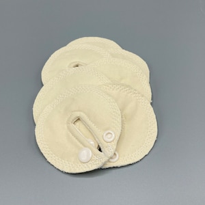 May include: A set of five off-white fabric pads with a small opening and a white button on each pad.