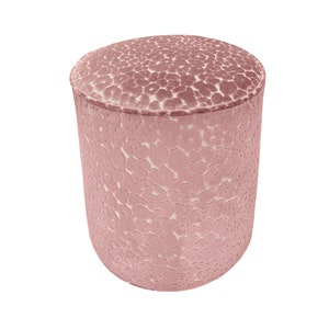 May include: A pink velvet ottoman with a white floral pattern. The ottoman is round and has a smooth surface.