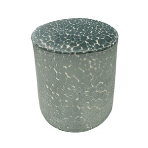 May include: A round, light blue ottoman with a white and light blue patterned design.