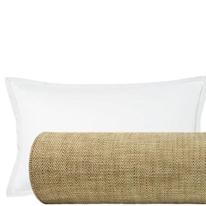 May include: A decorative bed arrangement featuring a tan bolster pillow with a woven texture, flanked by two white rectangular pillows. The bolster pillow has rounded ends and a neutral color, suitable for various bedroom decor styles.