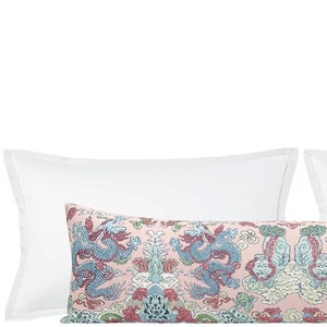 May include: A long decorative pillow with a pink background and a blue and red dragon pattern. The pillow is flanked by two white pillowcases.