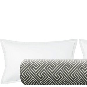 May include: A gray and white geometric patterned bolster pillow with two white standard pillowcases.