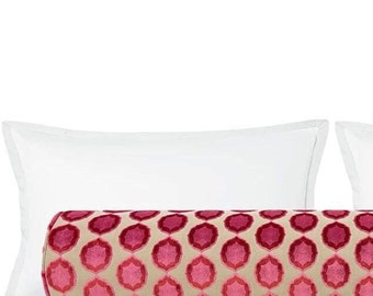 May include: A pink and white patterned bolster pillow with a geometric design. The pillow is placed on top of two white standard pillows.
