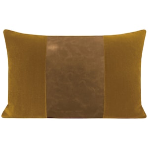 May include: A rectangular throw pillow with a brown leather center panel and mustard yellow velvet sides.