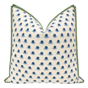 May include: Decorative throw pillow with a cream-colored background and a pattern of blue, stylized floral shapes. The pillow has a green border, adding a contrasting accent. This pillow is a stylish addition to any home decor.