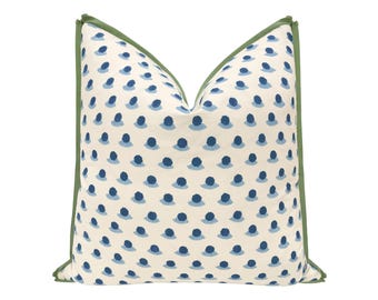 May include: Decorative throw pillow with a cream-colored background and a pattern of blue, stylized floral shapes. The pillow has a green border, adding a contrasting accent. This pillow is a stylish addition to any home decor.